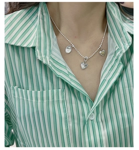 Detail of S925 silver beaded necklace with vintage heart and smiley face pendants