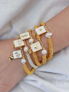 Detail of five-piece gold bead bracelets with baroque pearls and white enamel charms