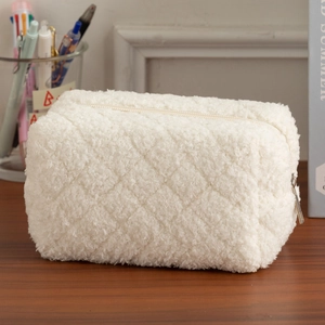 Close-up of cream quilted sherpa storage bag with zipper detail on wooden desk