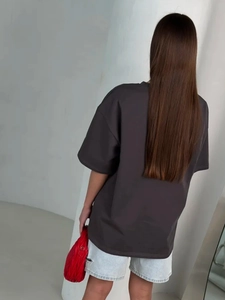 Rear view of an oversized dark grey t-shirt paired with a red pleated texture handbag