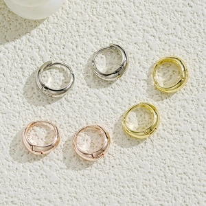 Detailed close-up of geometric C-shaped earrings in silver, gold, and rose gold finishes