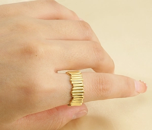 Close-up of golden stainless steel ring with vertical striped texture on a finger