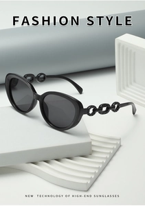 Detail shot of black cat eye sunglasses featuring unique chain temple design on stone base