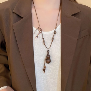 Detailed view of vintage wood gourd pendant necklace on a model wearing a brown blazer