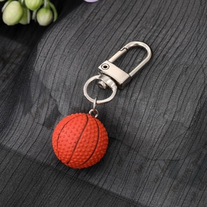 3D basketball keychain with orange textured ball and silver metal hook on black fabric