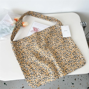Detailed macro view of yellow canvas tote bag with white daisy floral pattern and EMIS tag