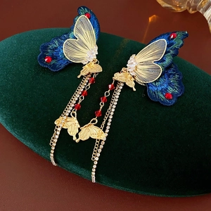 Nahaufnahme der Vintage Schmetterlings-Ohrringe mit blauer Stickerei und Goldketten
