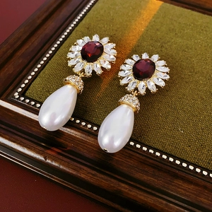 Macro shot of retro flower earring with wine red gemstone and white pearl drop