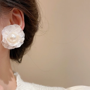 Detail view of elegant lace flower earrings with a pearl center on model