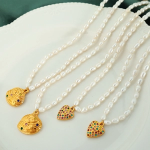 French freshwater pearl necklace with gold heart pendant on white porcelain plate