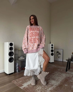 Detail of oversized pink knit sweater with Cyrillic text and white lace skirt
