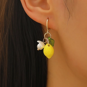 Detailed close-up of sweet yellow lemon pendant earrings with white flower and green leaf
