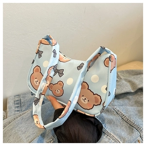 Detail of light blue canvas shoulder bag featuring cute bear and bow tie patterns