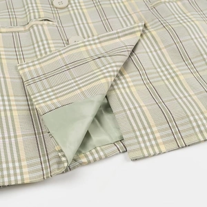 Detailed macro view of green plaid blazer pocket showing fabric texture and lining