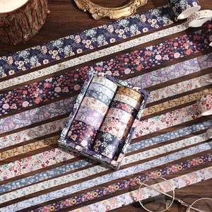 Flat lay of vintage floral washi tape set on dark wood with retro glasses and props