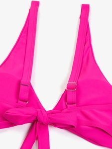 Dettaglio del top bikini fucsia con fibbia regolabile e nodo decorativo centrale
