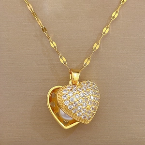 Detailed close-up of a golden heart locket necklace with white zircons and an inner pearl