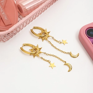 Détail de boucles d'oreilles étoiles et lunes dorées avec croissant de zircon blanc