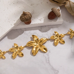 Detail shot of golden floral pendant necklace on white marble background with natural decor