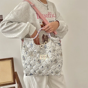 Close-up of quilted canvas bag with cartoon patterns and purple handle on a model