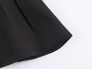 Close-up of black suit fabric texture and pleated hem detail with high-quality stitching
