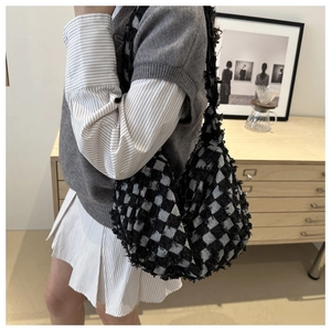 Detail shot of black and white checkered knit hobo bag with fringe edges on model