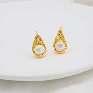 Macro view of water drop pearl earrings with golden hollow mesh in 18k gold plating