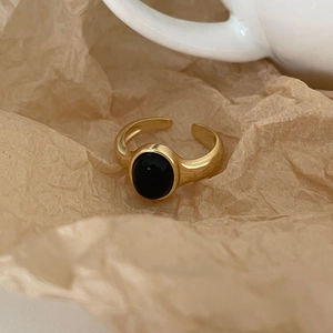 Gold-plated minimalist open ring featuring an oval black onyx stone on vintage paper