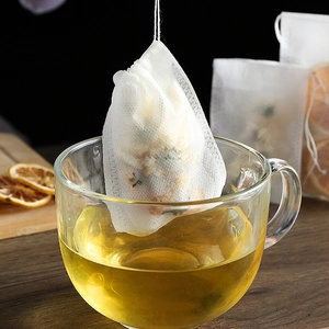 Disposable non-woven drawstring tea filter bag steeping in a clear glass cup