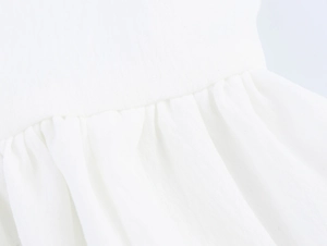 Detailed close-up showing the pleated texture and crochet stitching of the white summer dress