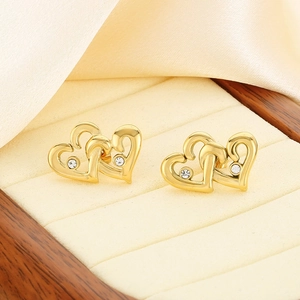 Macro detail of 18K gold-plated double heart stud earrings with sparkling diamonds