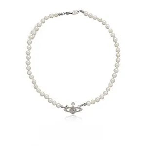 Detail of faux pearl necklace with sparkling rhinestone saturn planet pendant and silver clasp