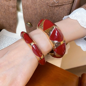 Macro shot of French retro red enamel and gold metallic thick cuff bracelets