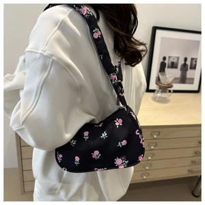 Detail of floral canvas underarm bag with pink roses pattern and knotted shoulder strap