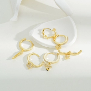Detail of gold earring set featuring micro-pave zircon bee and flower pendants