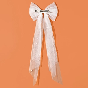 Elegant white tulle bow hair clip with long ribbons and pearl accents on orange background