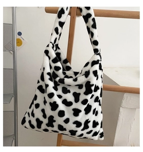 Furry cow print shoulder bag with large capacity and soft plush texture on wooden rack