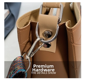 Detail of silver D-ring hardware and colorful woven strap on brown lychee texture bag