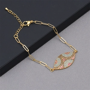 Close-up of golden paperclip chain bracelet with multicolor zircon evil eye charm