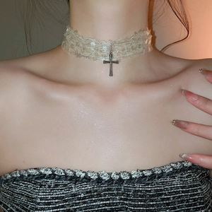 Gros plan du ras-du-cou en dentelle avec pendentif croix en métal et peau scintillante