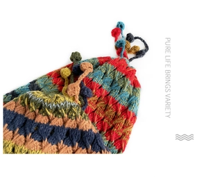 Close-up of colorful crochet knit hat detailing textured wool tassels and bohemian patterns