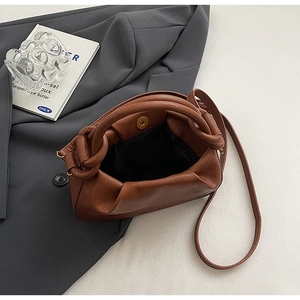 Dettaglio della borsa a mano plissettata in pelle marrone con chiusura magnetica