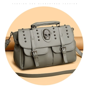Detail of grey leather crossbody bag featuring punk rivets and a skull emblem decoration