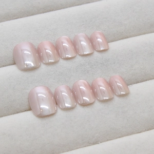 Nude pink cat eye press-on nails with shimmering pearl finish on gray display tray