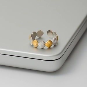 Detailed shot of alternating gold and silver shell-shaped scallops on adjustable steel ring