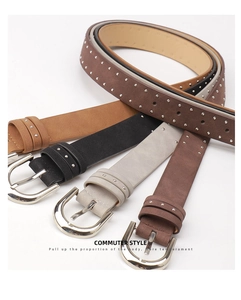 Macro shot of four suede leather belts with silver rivets in brown, black, and grey
