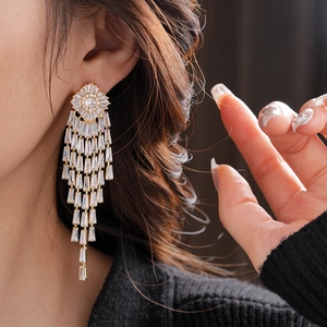 Close-up of gold-plated tassel earrings with sparkling zircon crystals on model