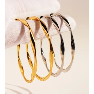 Classic wavy twist gold and silver chunky hoop earrings with polished metal finish