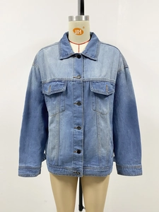 Detail of light blue washed denim jacket with classic collar and button-up chest pockets