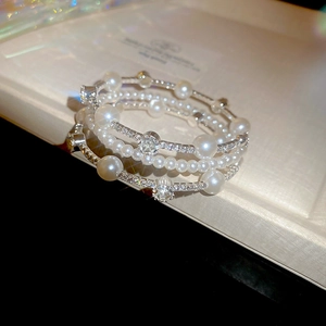 Detailed close-up of multilayered pearl and diamond bracelets in a white jewelry gift box